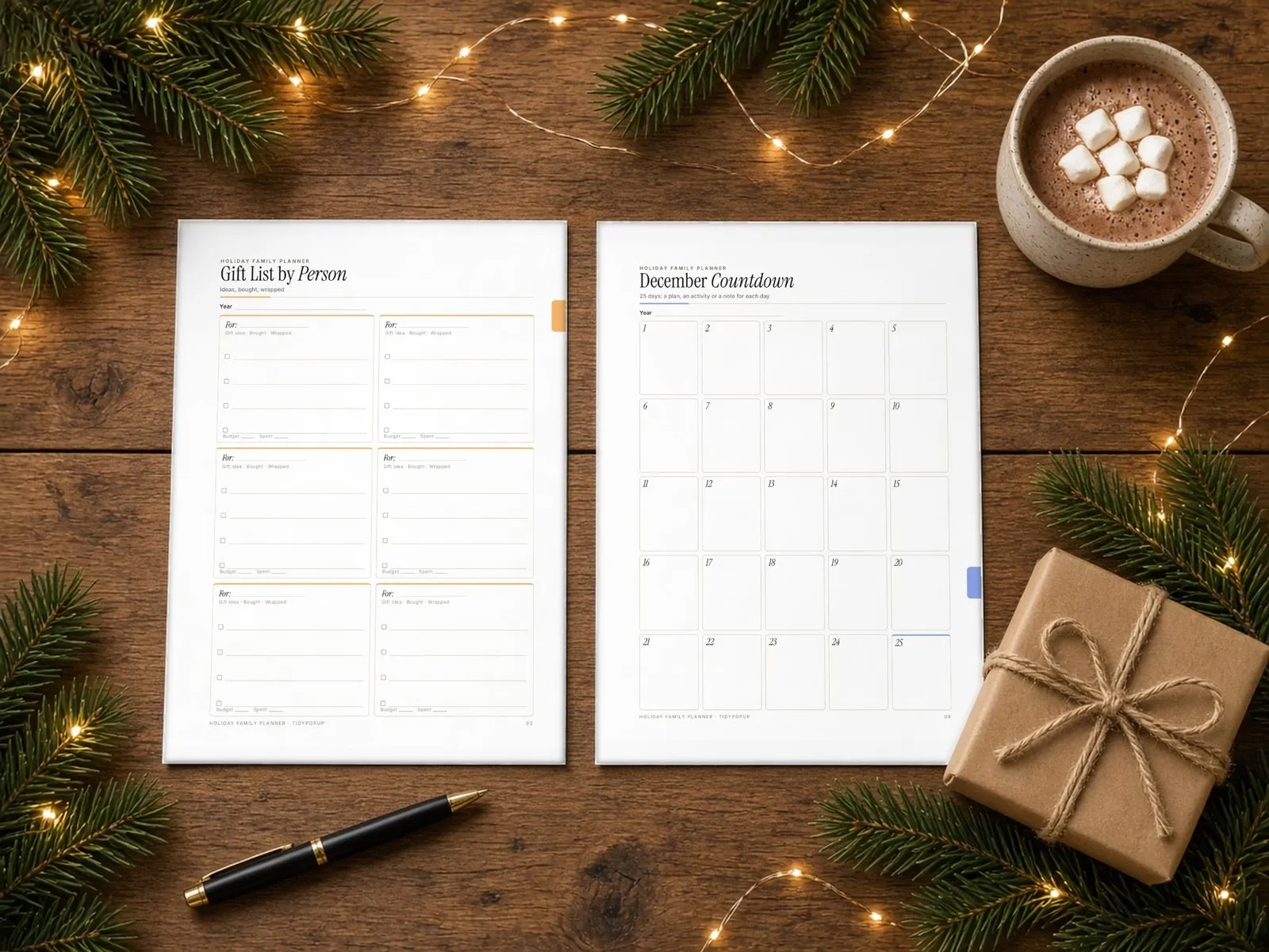 Illustrative styled scene: printed Holiday Gift List by Person and December Countdown pages on a wooden table with cocoa and string lights