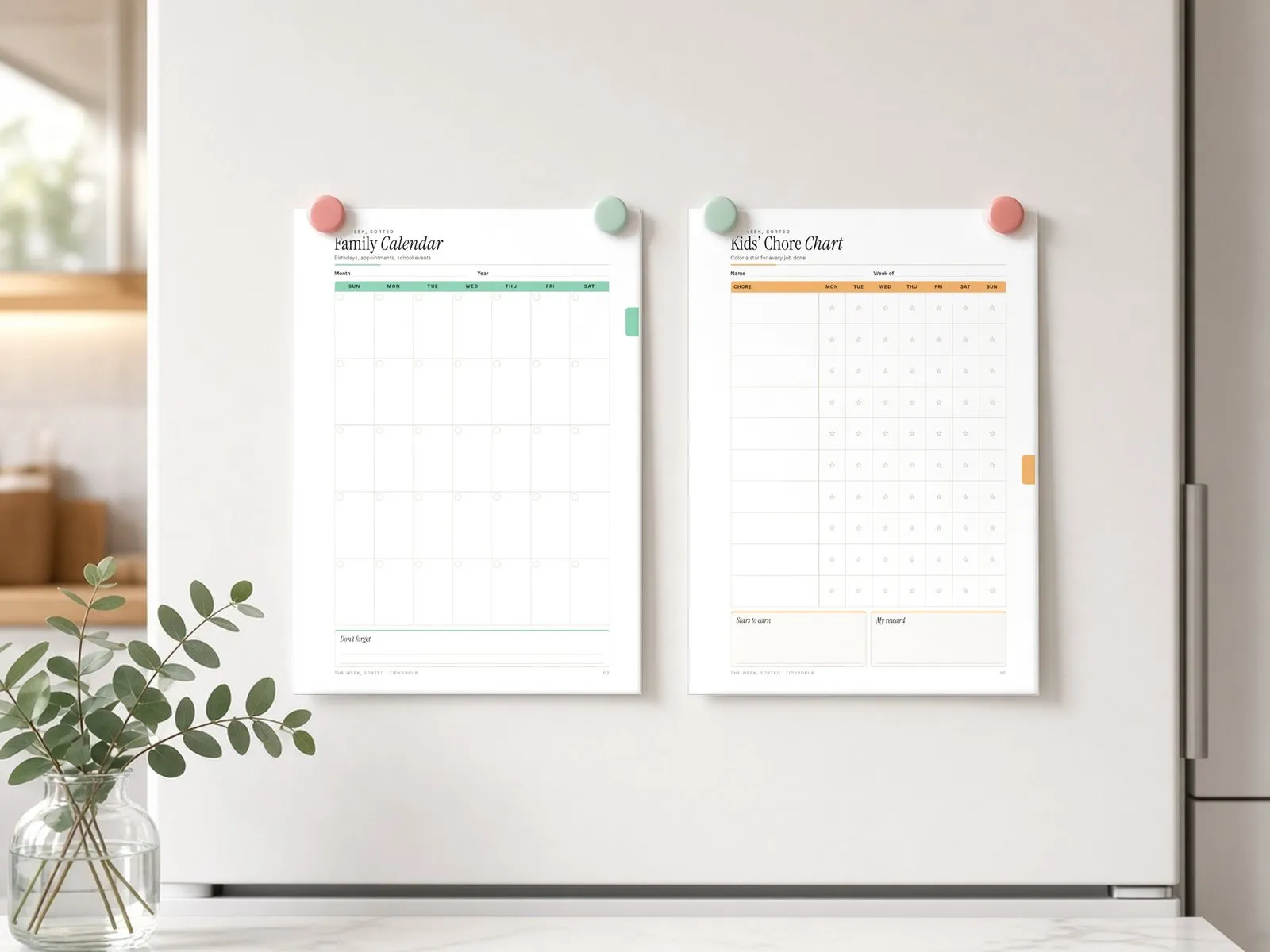 Illustrative styled scene: printed Family Calendar and Kids’ Chore Chart pages held on a fridge with magnets